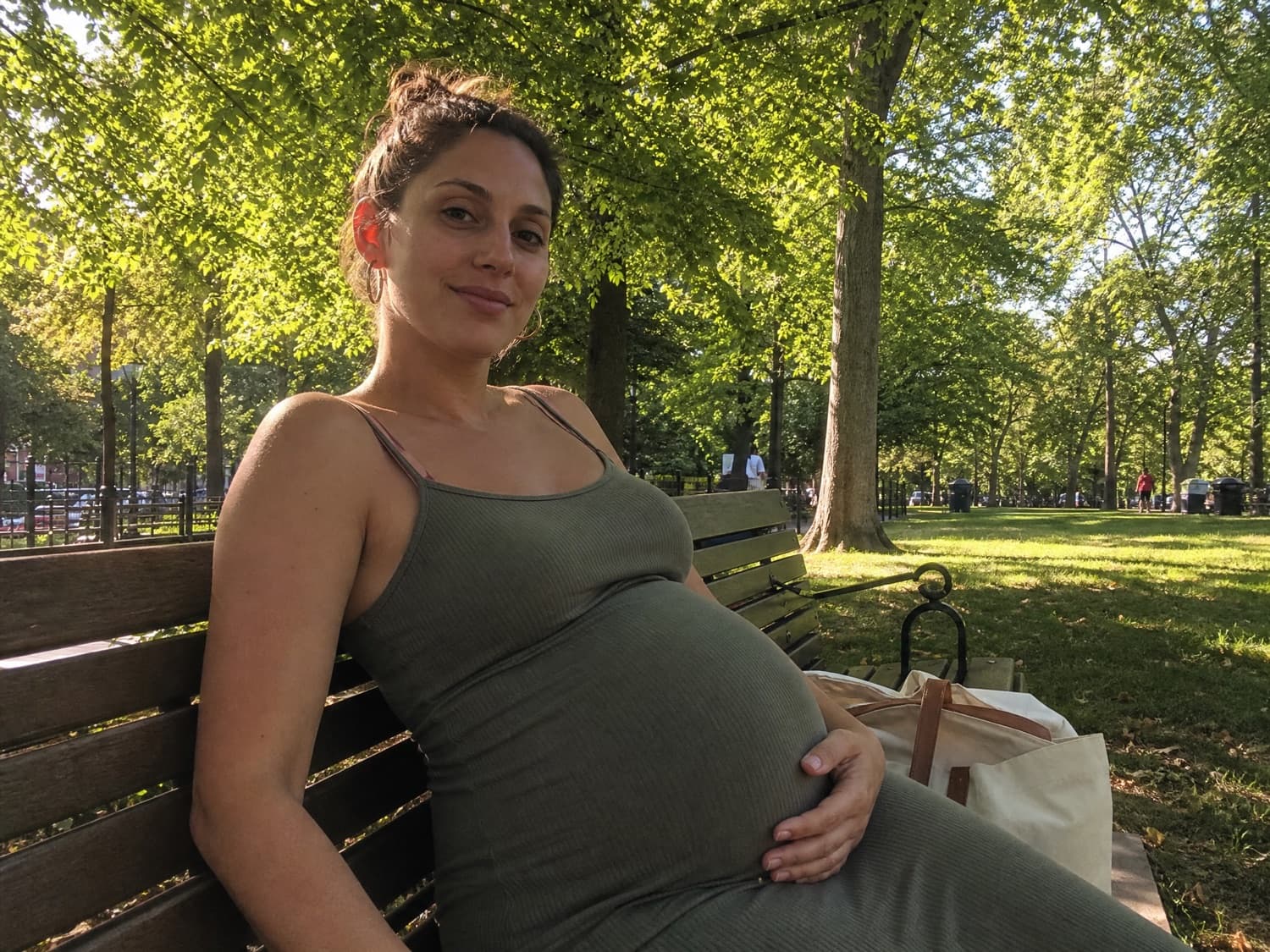 A pregnant surrogate mother relaxing on a park bench